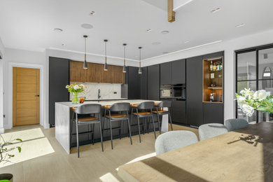 Contemporary l-shaped kitchen/diner in Other with a submerged sink, flat-panel cabinets, grey cabinets, white splashback, stone slab splashback, black appliances, an island, beige floors and white worktops.