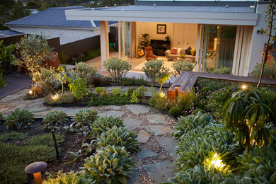 Photo of a mid-sized contemporary backyard garden in Auckland with natural stone pavers.