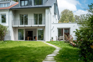 Mittelgroßes, Zweistöckiges Modernes Reihenhaus mit Putzfassade, weißer Fassadenfarbe, Satteldach und Ziegeldach in München