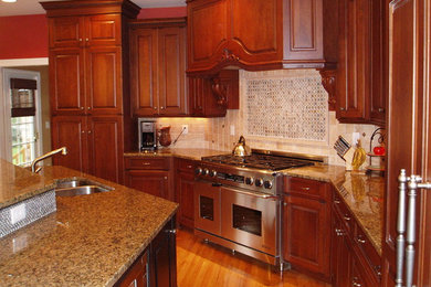 Photo of a traditional u-shaped eat-in kitchen in New York with a double-bowl sink, raised-panel cabinets, medium wood cabinets, granite benchtops, beige splashback, mosaic tile splashback and stainless steel appliances.