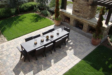 Modelo de patio contemporáneo grande sin cubierta en patio trasero con chimenea y adoquines de ladrillo