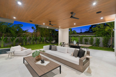 Patio - contemporary tile patio idea in Miami with a roof extension