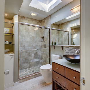 Bathroom - 1950s 3/4 beige tile beige floor bathroom idea in Detroit with flat-panel cabinets, brown cabinets, a one-piece toilet, beige walls, a vessel sink, glass countertops and white countertops