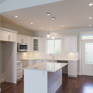 Idéer för ett gul skafferi, med en dubbel diskho, vita skåp, bänkskiva i kvarts, vitt stänkskydd, stänkskydd i keramik, rostfria vitvaror, mörkt trägolv, en köksö, brunt golv och skåp i shakerstil