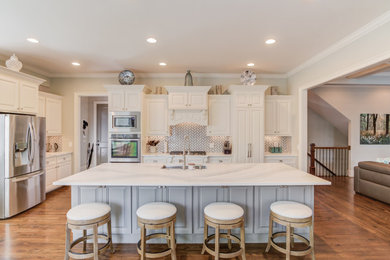 Inspiration for a large timeless l-shaped medium tone wood floor and brown floor eat-in kitchen remodel in Atlanta with a single-bowl sink, raised-panel cabinets, quartz countertops, glass tile backsplash, stainless steel appliances, an island and multicolored countertops