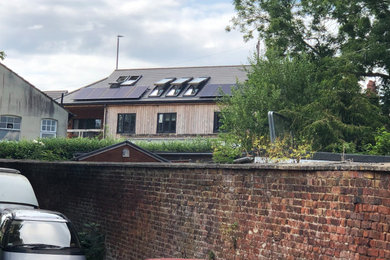 Inspiration for a large and beige rural two floor side detached house in Gloucestershire with wood cladding, a half-hip roof, a tiled roof, a grey roof and board and batten cladding.