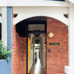 Foto di una porta d'ingresso tradizionale di medie dimensioni con pareti bianche, pavimento in legno massello medio, una porta singola e una porta gialla