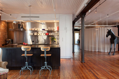 Small urban galley medium tone wood floor open concept kitchen photo in New York with an integrated sink, open cabinets, stainless steel cabinets, soapstone countertops, metallic backsplash, stainless steel appliances and an island
