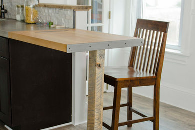 Eat-in kitchen - mid-sized eclectic galley laminate floor eat-in kitchen idea in Other with an integrated sink, shaker cabinets, black cabinets, concrete countertops, white backsplash, stone tile backsplash, stainless steel appliances and a peninsula