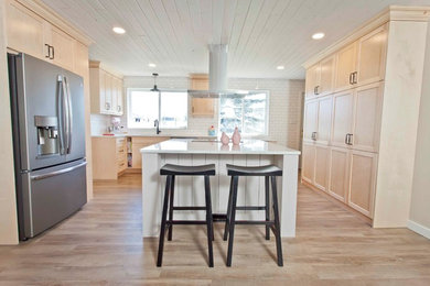 Inspiration for a large arts and crafts u-shaped open plan kitchen in Calgary with an undermount sink, shaker cabinets, light wood cabinets, quartz benchtops, white splashback, subway tile splashback, stainless steel appliances, light hardwood floors, with island, beige floor and white benchtop.