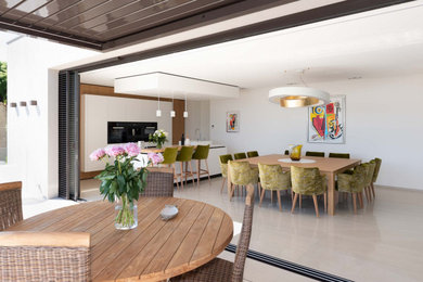 Aménagement d'une très grande cuisine ouverte linéaire contemporaine avec un évier intégré, un placard à porte affleurante, des portes de placard blanches, un plan de travail en quartz, un électroménager noir, un sol en carrelage de céramique, îlot, un sol beige et un plan de travail blanc.