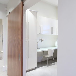 Inredning av ett modernt stort arbetsrum, med vita väggar, ett inbyggt skrivbord och skiffergolv