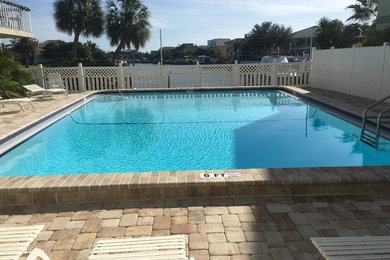 Example of a mid-sized beach style courtyard brick and rectangular lap pool design in Tampa
