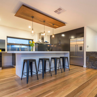 Design ideas for a large contemporary kitchen pantry in Canberra - Queanbeyan with a double-bowl sink, black cabinets, stainless steel benchtops, mirror splashback, stainless steel appliances, medium hardwood floors and with island.