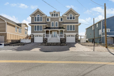 Inspiration for a large beach style three-storey beige house exterior in New York with vinyl siding, a gable roof and a shingle roof.