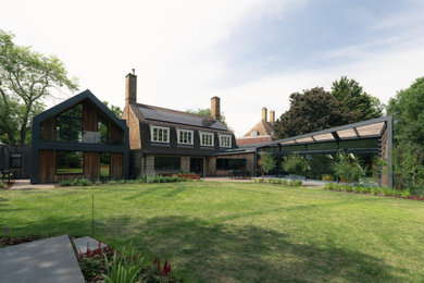 Expansive and multi-coloured contemporary two floor rear house exterior in Cambridgeshire with wood cladding, a pitched roof, a mixed material roof, a brown roof and board and batten cladding.