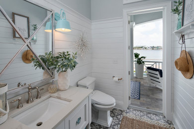 Example of a beach style gray floor, single-sink, shiplap wall and wainscoting bathroom design in Tampa with recessed-panel cabinets, white cabinets, gray walls, an undermount sink, beige countertops and a freestanding vanity