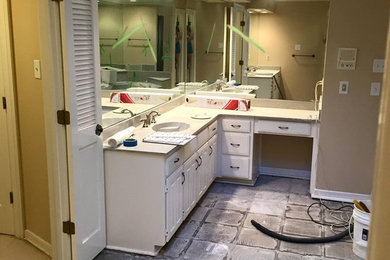 Cette image montre une salle de bain avec un placard à porte shaker, des portes de placard blanches, une baignoire posée, des carreaux de porcelaine, un mur gris, un sol en carrelage de porcelaine et un plan de toilette en quartz.