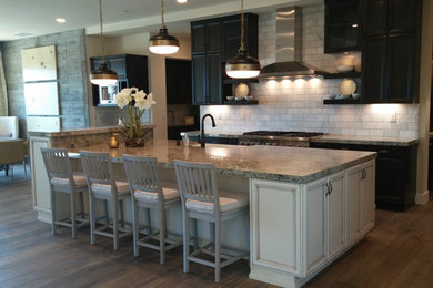 Open concept kitchen - mid-sized transitional l-shaped medium tone wood floor and brown floor open concept kitchen idea in San Francisco with a farmhouse sink, recessed-panel cabinets, dark wood cabinets, granite countertops, gray backsplash, stone tile backsplash, stainless steel appliances, an island and gray countertops