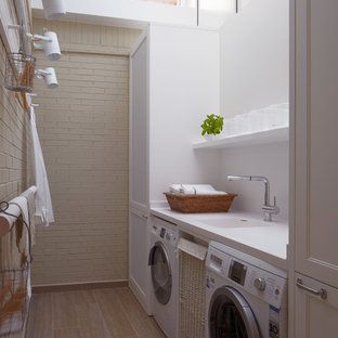 Inspiration for a medium sized urban single-wall separated utility room in Barcelona with a single-bowl sink, white walls, a side by side washer and dryer, recessed-panel cabinets and white cabinets.