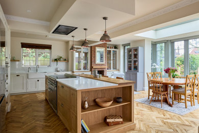 Inspiration for a large classic l-shaped open plan kitchen in London with a belfast sink, shaker cabinets, white cabinets, quartz worktops, grey splashback, engineered quartz splashback, stainless steel appliances, medium hardwood flooring, an island, brown floors, grey worktops, a drop ceiling and a chimney breast.