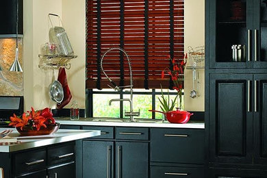 Example of a cottage kitchen design in Other with a double-bowl sink, solid surface countertops, stainless steel appliances, an island, flat-panel cabinets and black cabinets