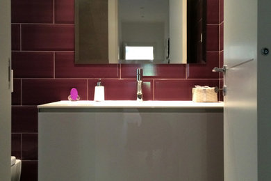 ローマにある広いモダンスタイルのおしゃれなマスターバスルーム (フラットパネル扉のキャビネット、白いキャビネット、アルコーブ型浴槽、分離型トイレ、ピンクのタイル、セラミックタイル、紫の壁、磁器タイルの床、一体型シンク、人工大理石カウンター、グレーの床、白い洗面カウンター、洗面台1つ、フローティング洗面台、白い天井) の写真