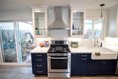 Enclosed kitchen - small modern galley porcelain tile and brown floor enclosed kitchen idea in Los Angeles with a farmhouse sink, shaker cabinets, blue cabinets, quartz countertops, white backsplash, porcelain backsplash, stainless steel appliances, no island and white countertops