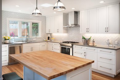 Inspiration for a mid-sized contemporary l-shaped eat-in kitchen remodel in San Francisco with an island, white cabinets, quartz countertops, gray backsplash, glass tile backsplash, stainless steel appliances and an undermount sink