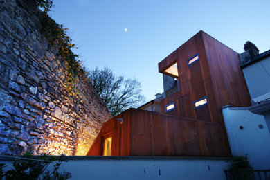 Diseño de fachada de casa pareada marrón actual con revestimiento de madera, tejado plano y panel y listón
