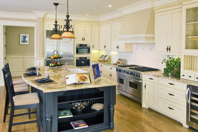 Example of a large classic l-shaped medium tone wood floor and brown floor eat-in kitchen design in Jacksonville with a farmhouse sink, beaded inset cabinets, beige cabinets, granite countertops, beige backsplash, ceramic backsplash, stainless steel appliances and an island