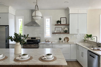 Mid-sized transitional l-shaped laminate floor and beige floor kitchen photo in DC Metro with an undermount sink, shaker cabinets, white backsplash, ceramic backsplash, stainless steel appliances, an island and beige countertops