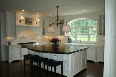 Eat-in kitchen - traditional u-shaped eat-in kitchen idea in Cincinnati with a farmhouse sink, beaded inset cabinets, white cabinets, marble countertops, white backsplash, subway tile backsplash and paneled appliances