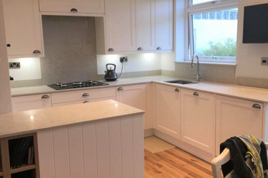 This is an example of a medium sized contemporary u-shaped kitchen in London with a submerged sink, shaker cabinets, beige cabinets, quartz worktops, beige splashback, granite splashback, integrated appliances, medium hardwood flooring, a breakfast bar, beige floors and beige worktops.