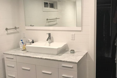 Example of a small 1960s master subway tile porcelain tile and black floor alcove shower design in Other with furniture-like cabinets, white cabinets, a wall-mount toilet, white walls, a vessel sink, quartz countertops, a hinged shower door and white countertops