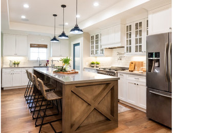 Mid-sized l-shaped medium tone wood floor eat-in kitchen photo in San Diego with a farmhouse sink, shaker cabinets, white cabinets, quartz countertops, white backsplash, ceramic backsplash, stainless steel appliances and an island