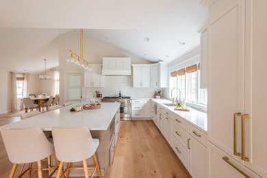 Eat-in kitchen - huge transitional l-shaped light wood floor and brown floor eat-in kitchen idea in Boston with an undermount sink, shaker cabinets, white cabinets, quartz countertops, white backsplash, ceramic backsplash, stainless steel appliances, an island and white countertops