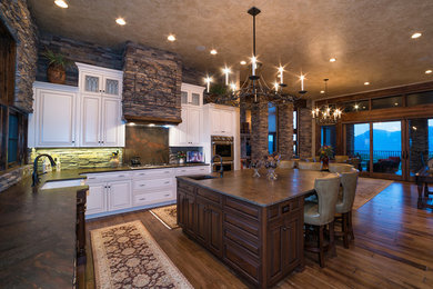 Elegant u-shaped eat-in kitchen photo with a farmhouse sink, raised-panel cabinets, white cabinets, granite countertops and an island