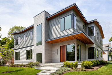 Inspiration for a large contemporary two-storey grey house exterior in Providence with concrete fiberboard siding and a flat roof.