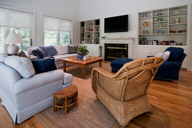 Inspiration for a large coastal open concept medium tone wood floor family room remodel in New York with white walls, a standard fireplace, a plaster fireplace and a wall-mounted tv
