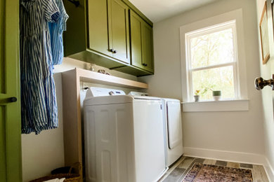 Inspiration for a mid-sized farmhouse single-wall porcelain tile dedicated laundry room remodel in Atlanta with shaker cabinets, green cabinets, wood countertops, gray walls and a side-by-side washer/dryer
