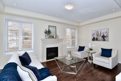 Example of a minimalist formal and open concept dark wood floor and brown floor living room design in Toronto with beige walls, a standard fireplace, a concrete fireplace and a wall-mounted tv