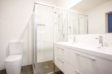 Inspiration for a contemporary bathroom in Canberra - Queanbeyan with a corner shower, white tile, ceramic tile, white walls, porcelain floors, an integrated sink, grey floor and white benchtops.