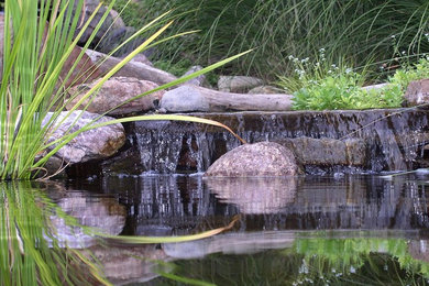 Photo of a mid-sized traditional full sun front yard stone water fountain landscape in Kansas City.