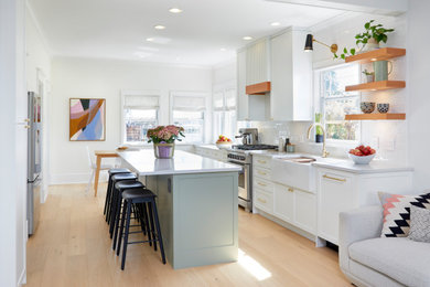 Kitchen - coastal kitchen idea in Other with shaker cabinets, white cabinets, white backsplash, stainless steel appliances and an island