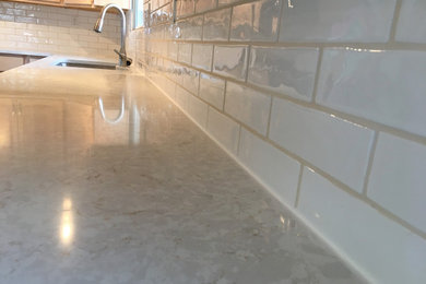 Example of a large transitional l-shaped laminate floor and multicolored floor eat-in kitchen design in Salt Lake City with an undermount sink, raised-panel cabinets, light wood cabinets, quartz countertops, white backsplash, ceramic backsplash, stainless steel appliances and white countertops