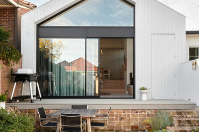 Photo of a small contemporary one-storey grey house exterior in Sydney with a gable roof, a metal roof and a grey roof.