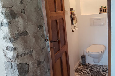 Aménagement d'un WC suspendu avec un mur blanc et carreaux de ciment au sol.