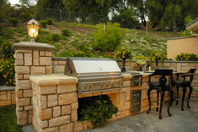 Inspiration for a large mediterranean backyard patio in Los Angeles with an outdoor kitchen, natural stone pavers and no cover.