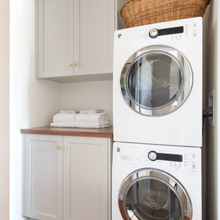 サンディエゴの小さいミッドセンチュリースタイルのおしゃれなランドリークローゼット (シェーカースタイル扉のキャビネット、白い壁、ライムストーンの床、上下配置の洗濯機・乾燥機、ベージュの床、グレーのキャビネット、木材カウンター) の写真